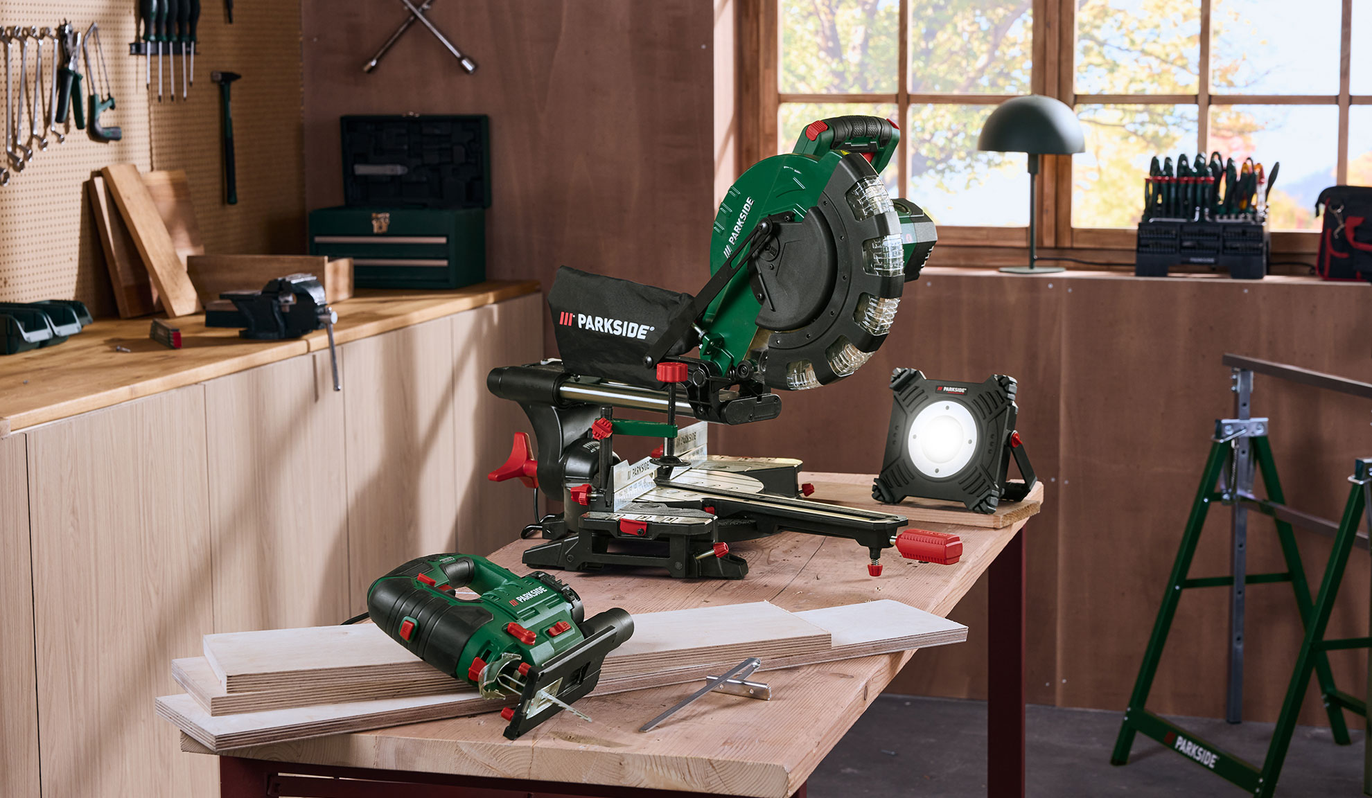 Kappsäge, Stichsäge und Arbeitsleuchte in einer Holzwerkstatt.