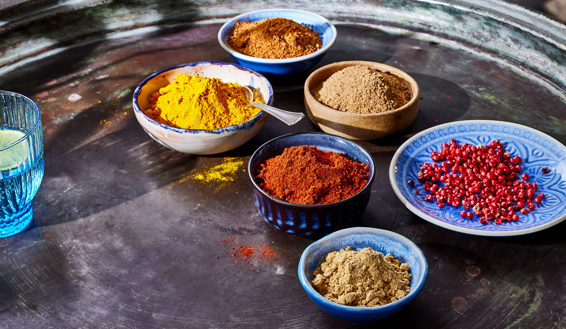 Verschiedene Gewürze in Schalen: Kurkuma, Paprika, Pfeffer und andere auf einem Metalltablett.