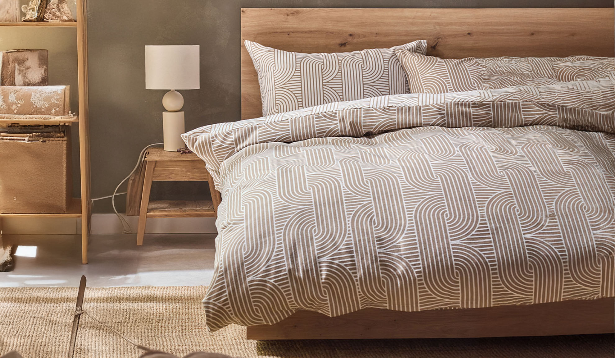 Schlafzimmer mit Holzbett, geometrischer Bettwäsche und Nachttisch mit Lampe.