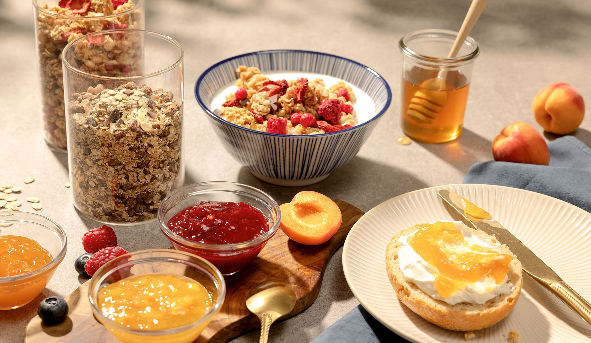 Frühstück mit Müsli, Honig, Marmelade und frischem Obst.