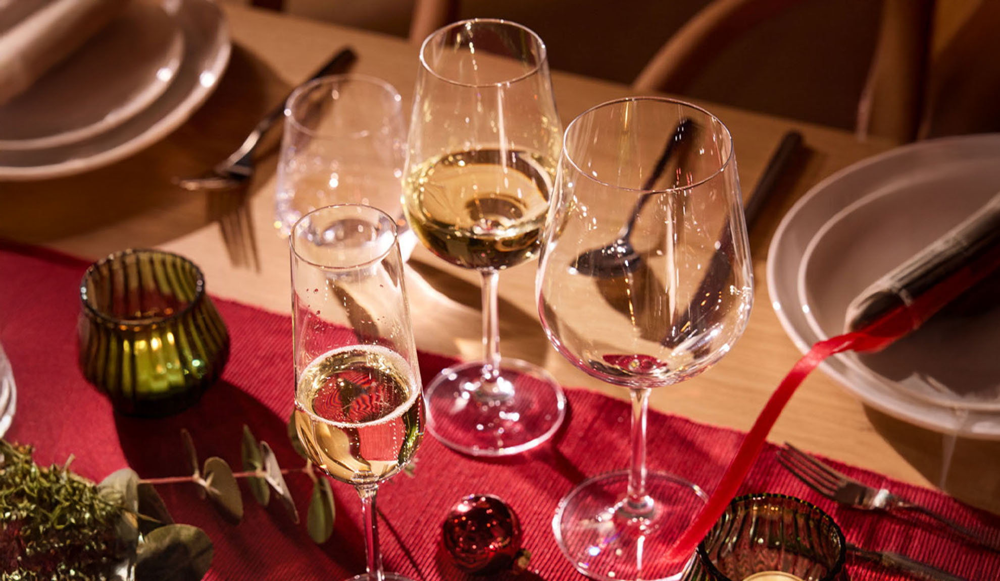 Festlich gedeckter Tisch mit Weingläsern, Sektglas und Weihnachtsdekoration.