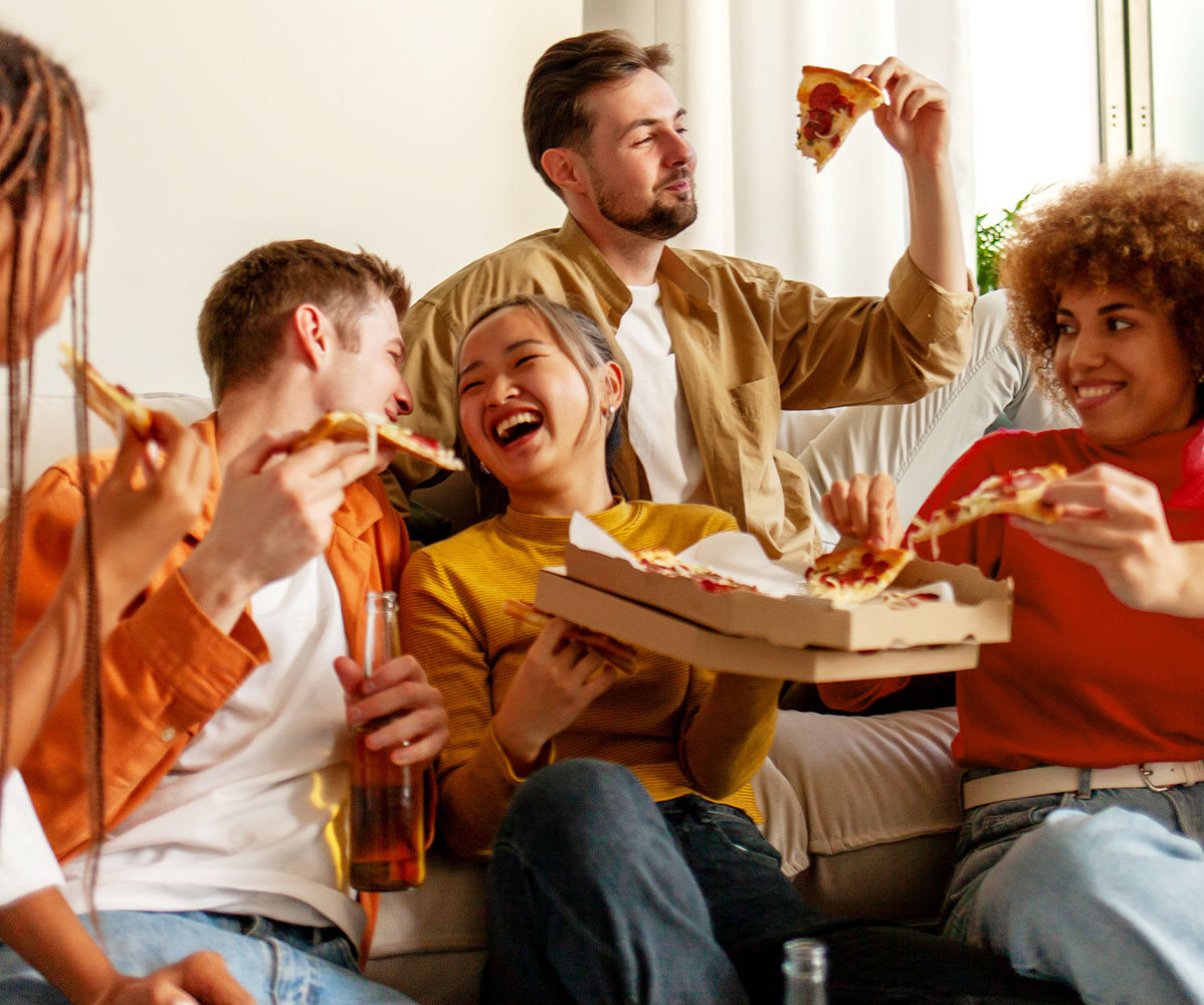 Freunde snacken Fingerfood auf einer Couch.