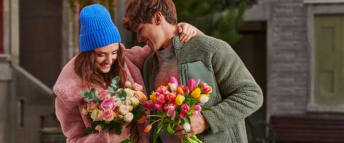Ein verliebtes Paar mit verschiedenen schönen Blumen in der Hand