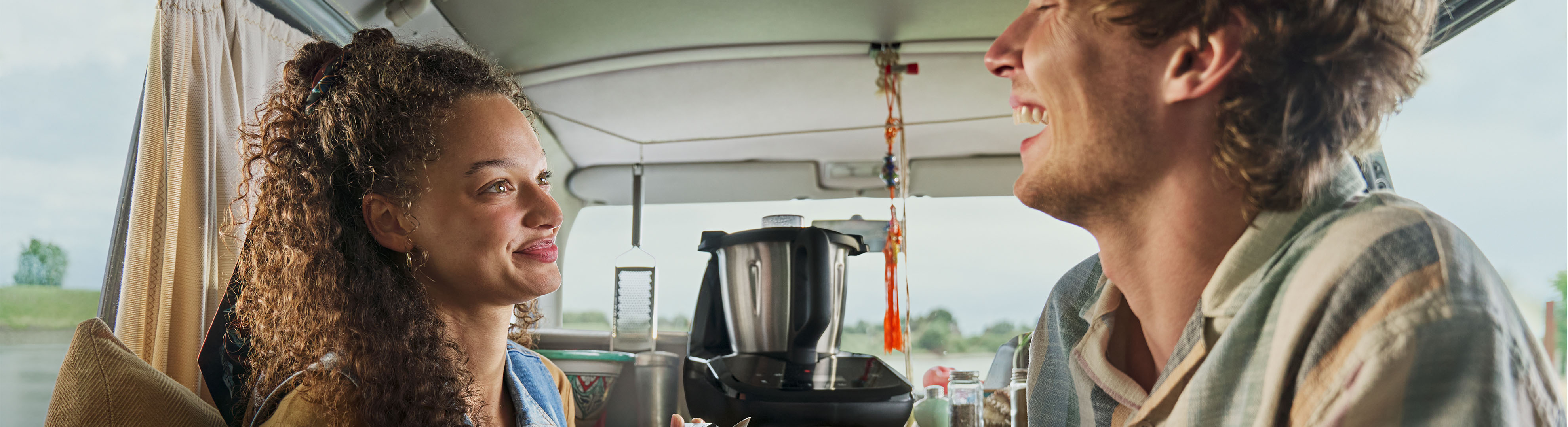 Paar lacht in einem Wohnmobil mit einer Küchenmaschine auf der Theke.