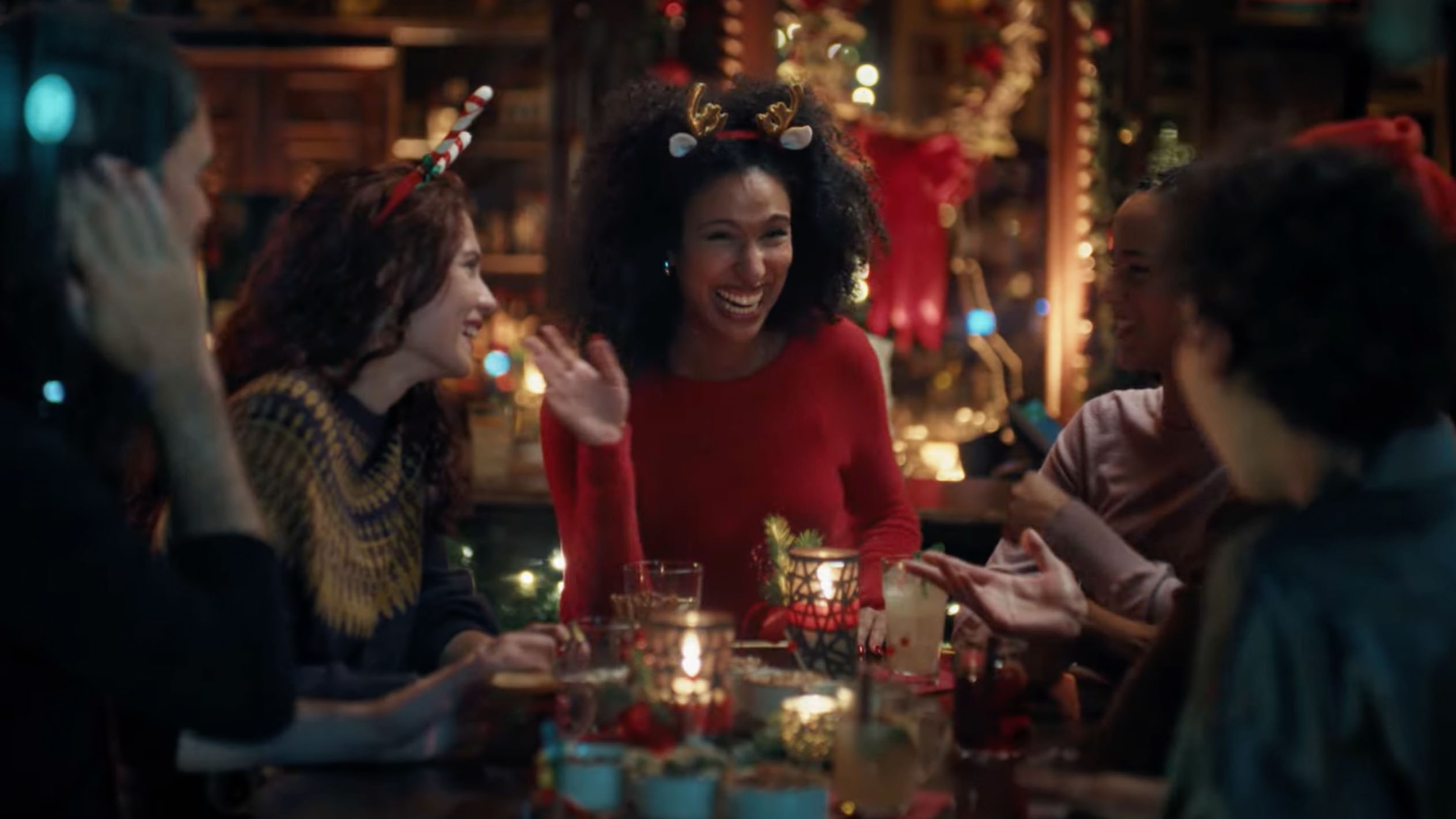 Freundinnen feiern Weihnachten mit Getränken und Snacks in einer festlich dekorierten Bar.