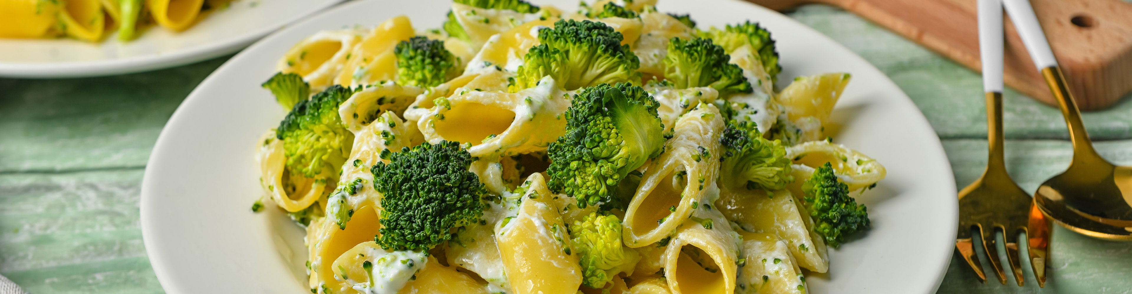 Nudeln mit Brokkoli und cremiger Soße auf einem weißen Teller