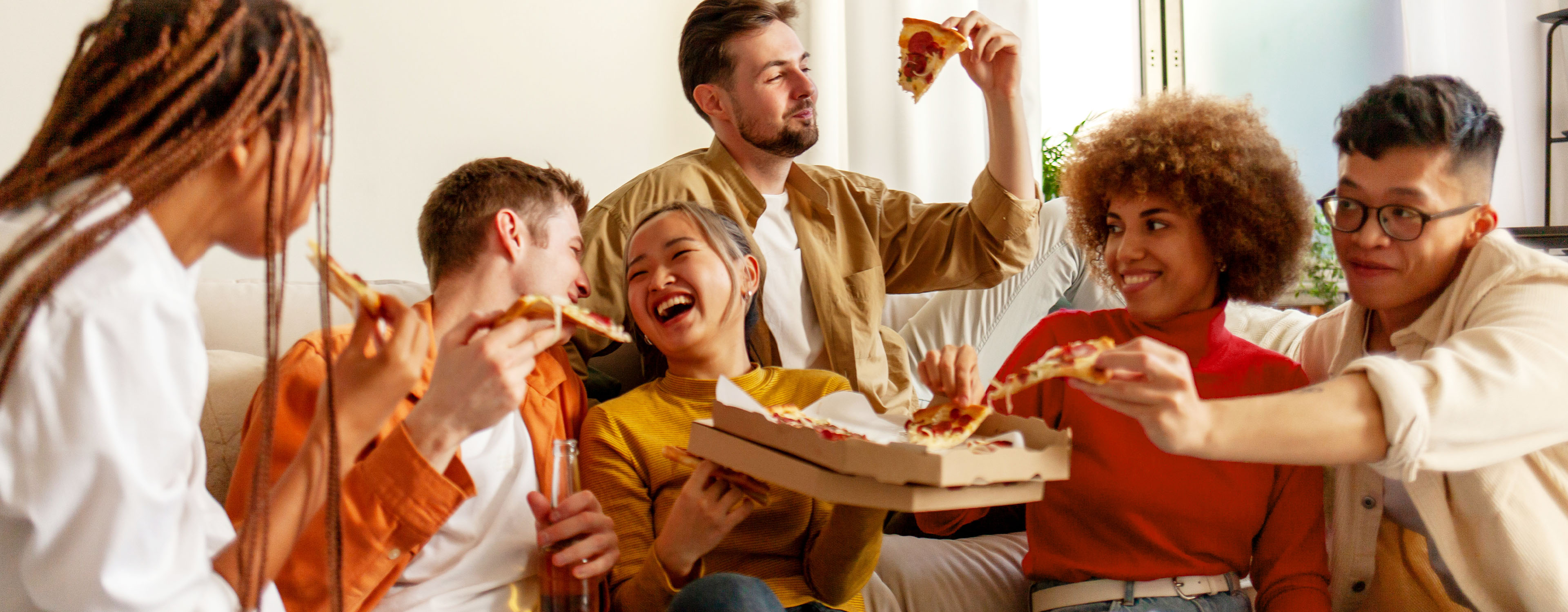 Freunde snacken Fingerfood auf einer Couch.
