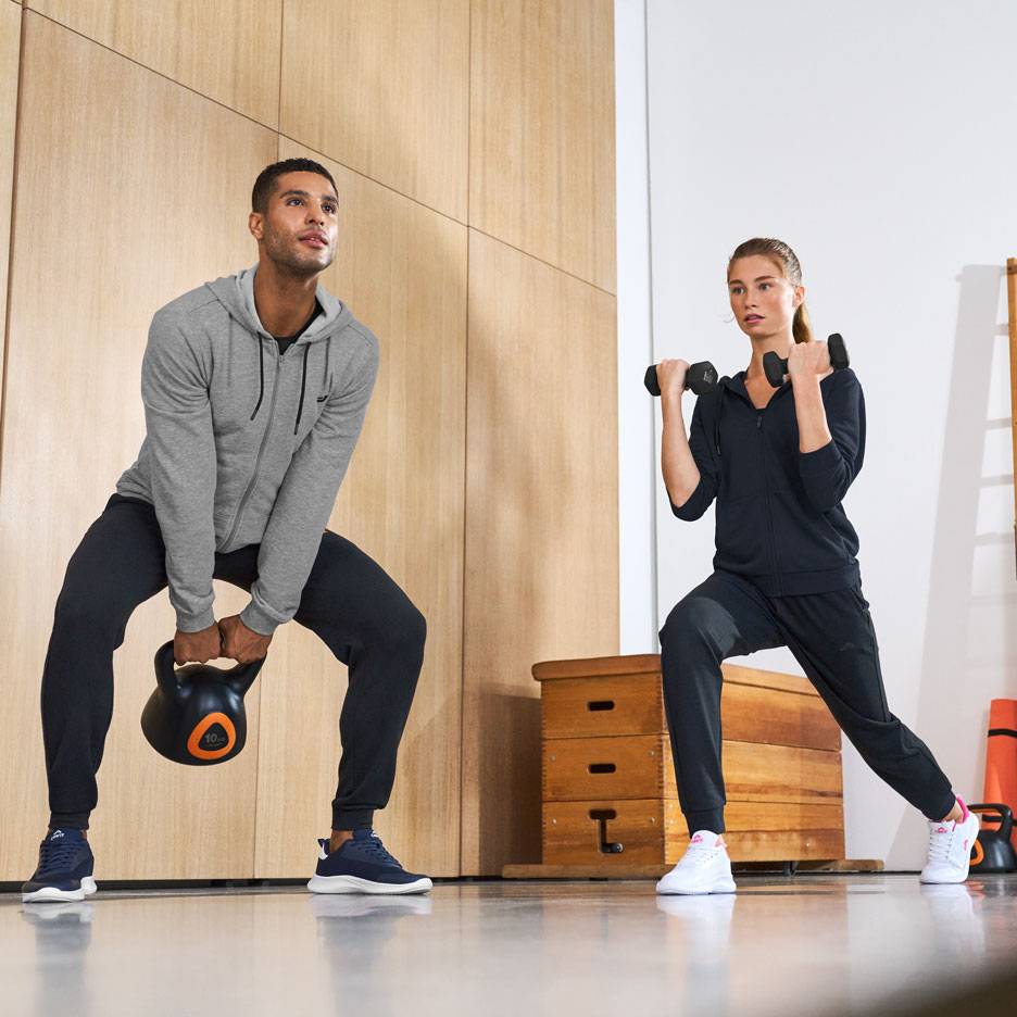 Mann und Frau in Sportkleidung, trainieren mit Kettlebell und Hanteln.