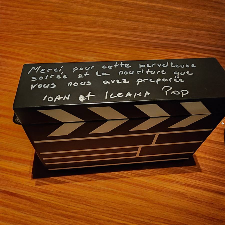 Schwarze Filmklappe mit handgeschriebenem Dankestext auf Französisch.