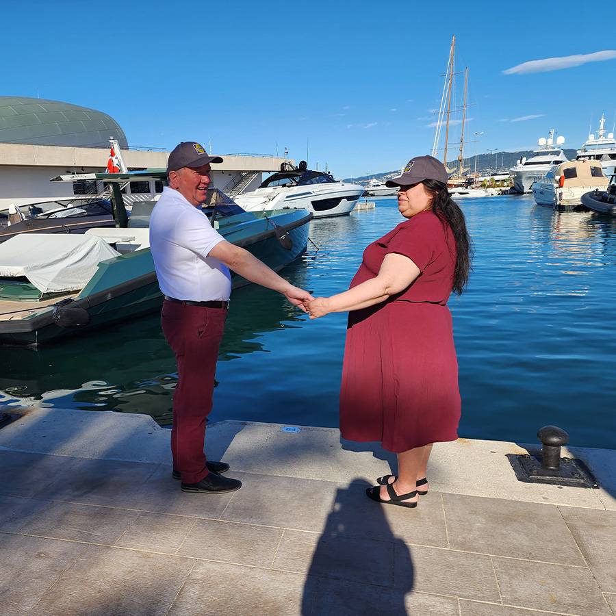 Ein Paar hält Händchen am Hafen, umgeben von Booten und Yachten.