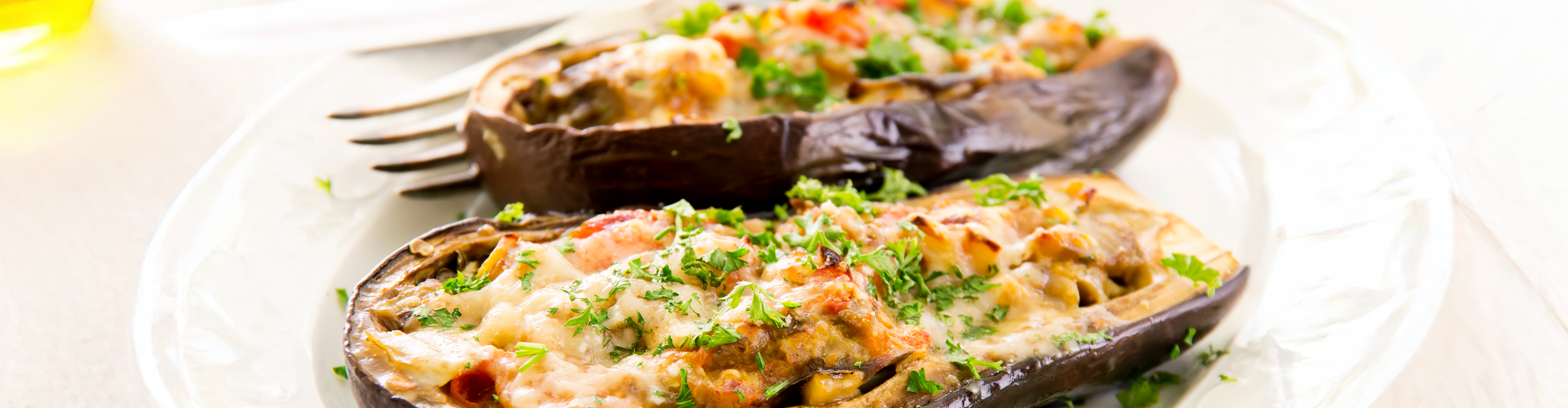 Gefüllte Auberginen mit Käse und Kräutern auf einem weißen Teller