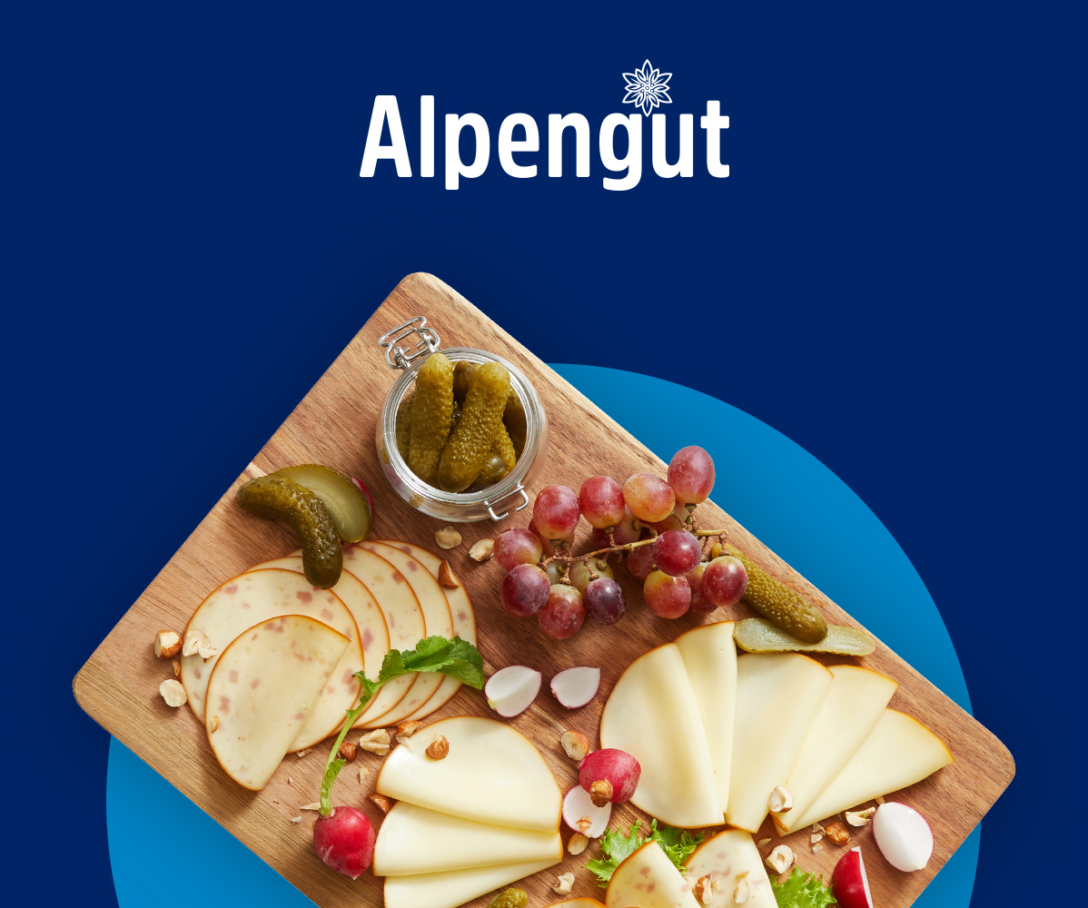 Alpengut Käse- und Wurstplatte mit Weintrauben, Gurken und Radieschen.