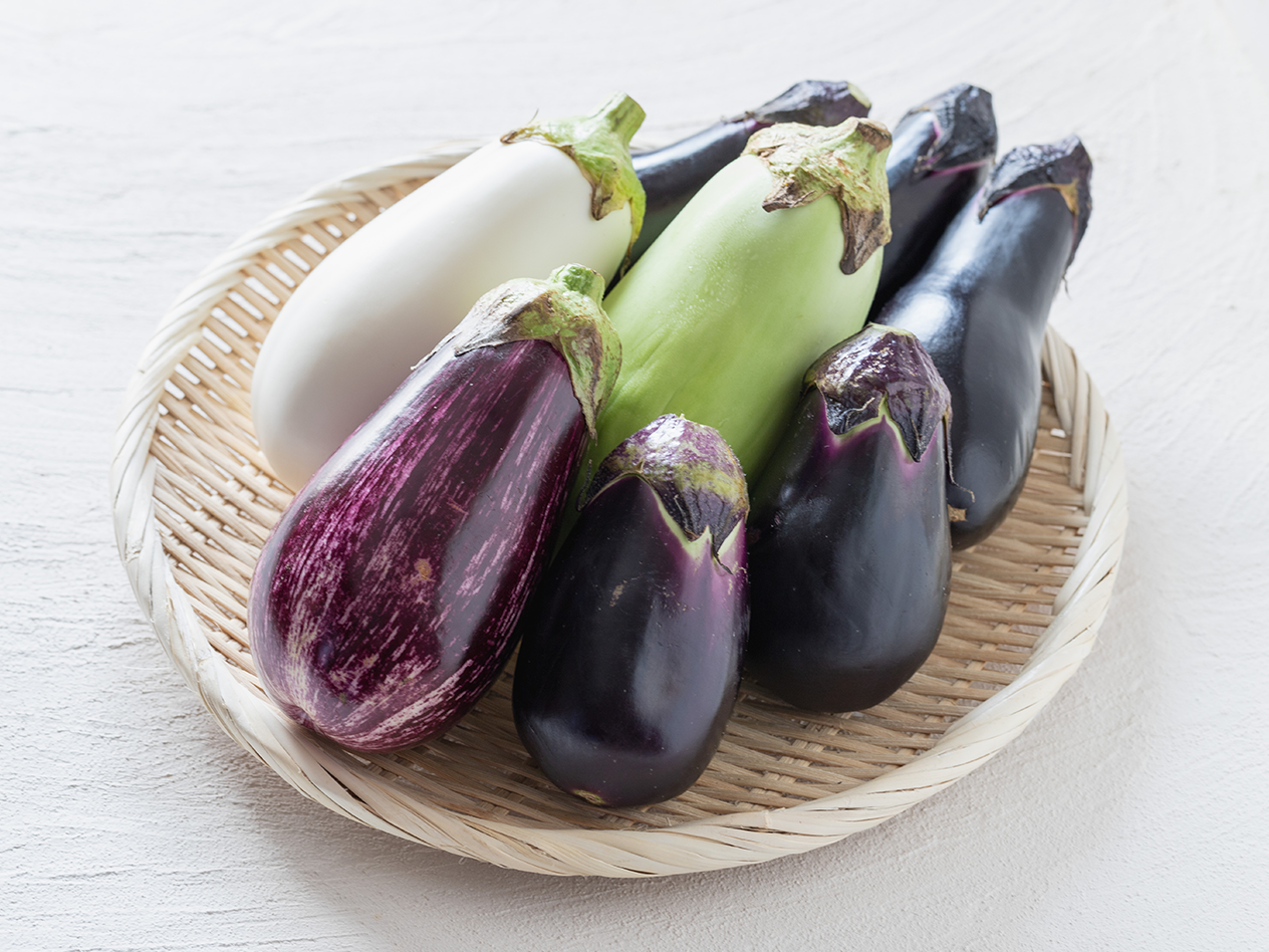 Verschiedene Auberginen in Weiß, Grün, Violett und Schwarz auf einem Korb