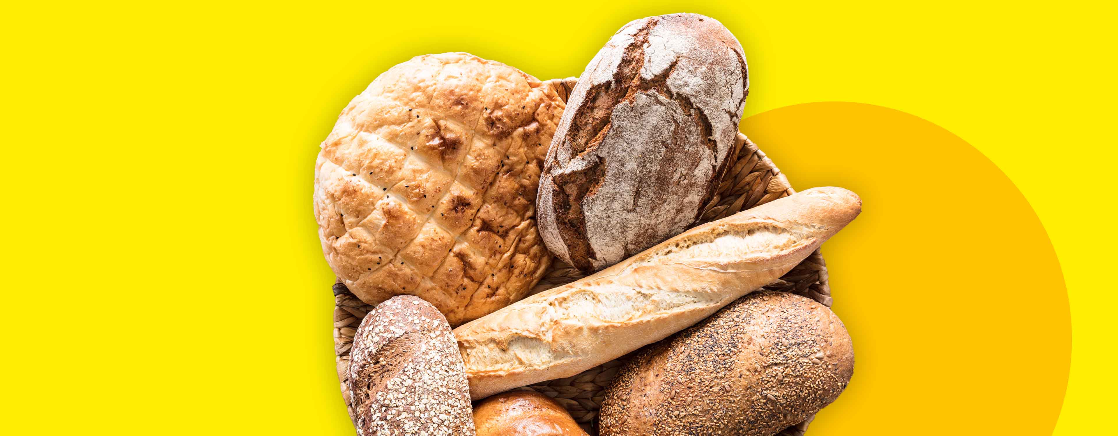 Ein Korb mit verschiedenen Brotsorten, darunter ein Bauernbrot, Baguette und Körnerbrot, auf gelbem Hintergrund.