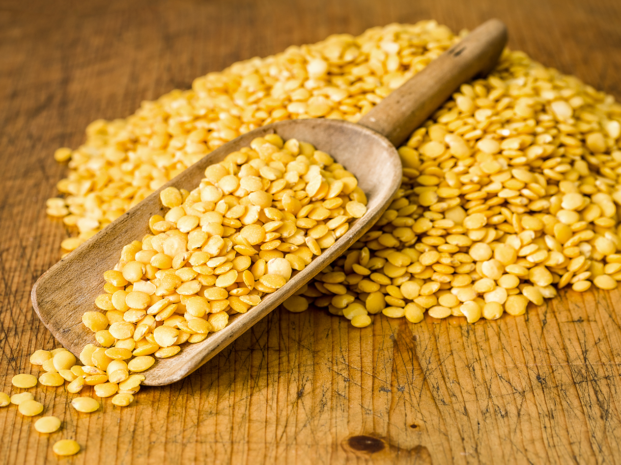 Gelbe Linsen auf einem Holztisch mit einer Holzschaufel