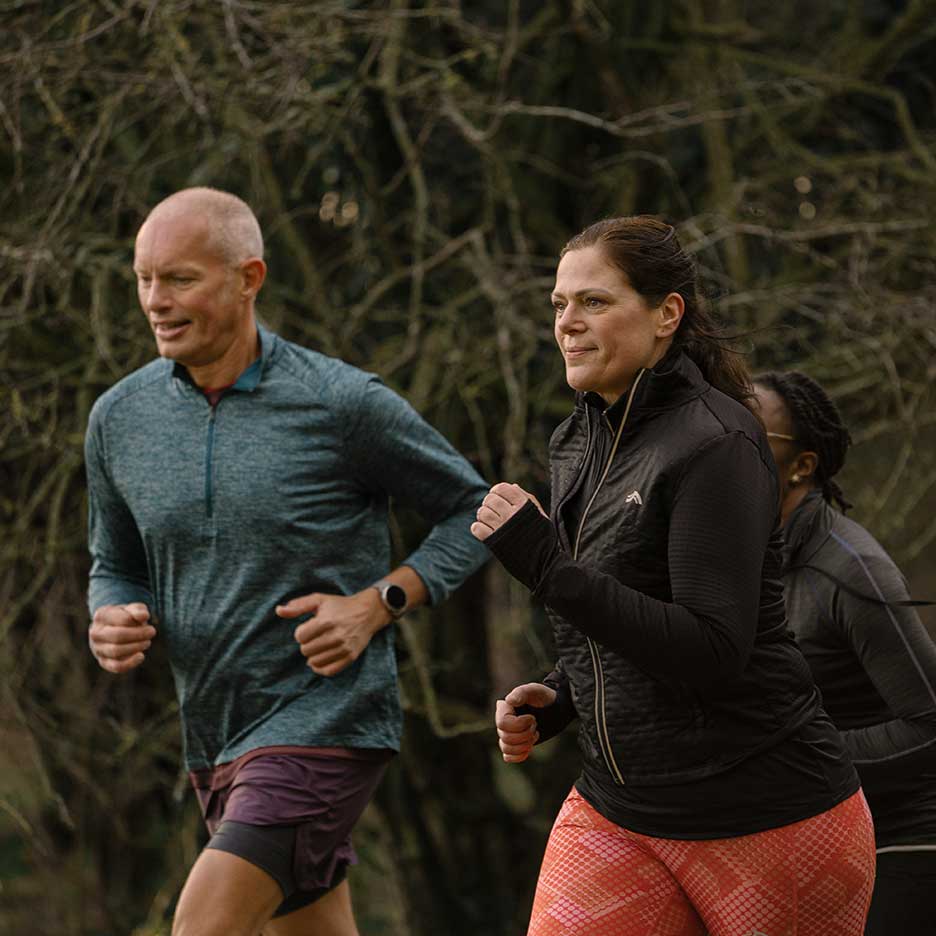 Zwei erwachsene Läufer in Sportkleidung joggen im Freien.