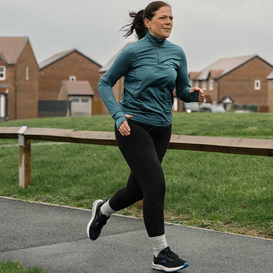 Frau in Sportkleidung läuft auf einem Outdoor-Weg.