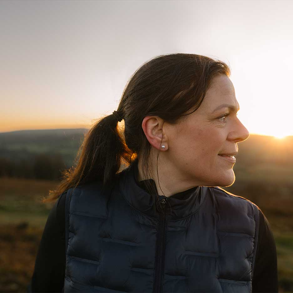 Frau in schwarzer Weste und schwarzem Pullover bei Sonnenuntergang.