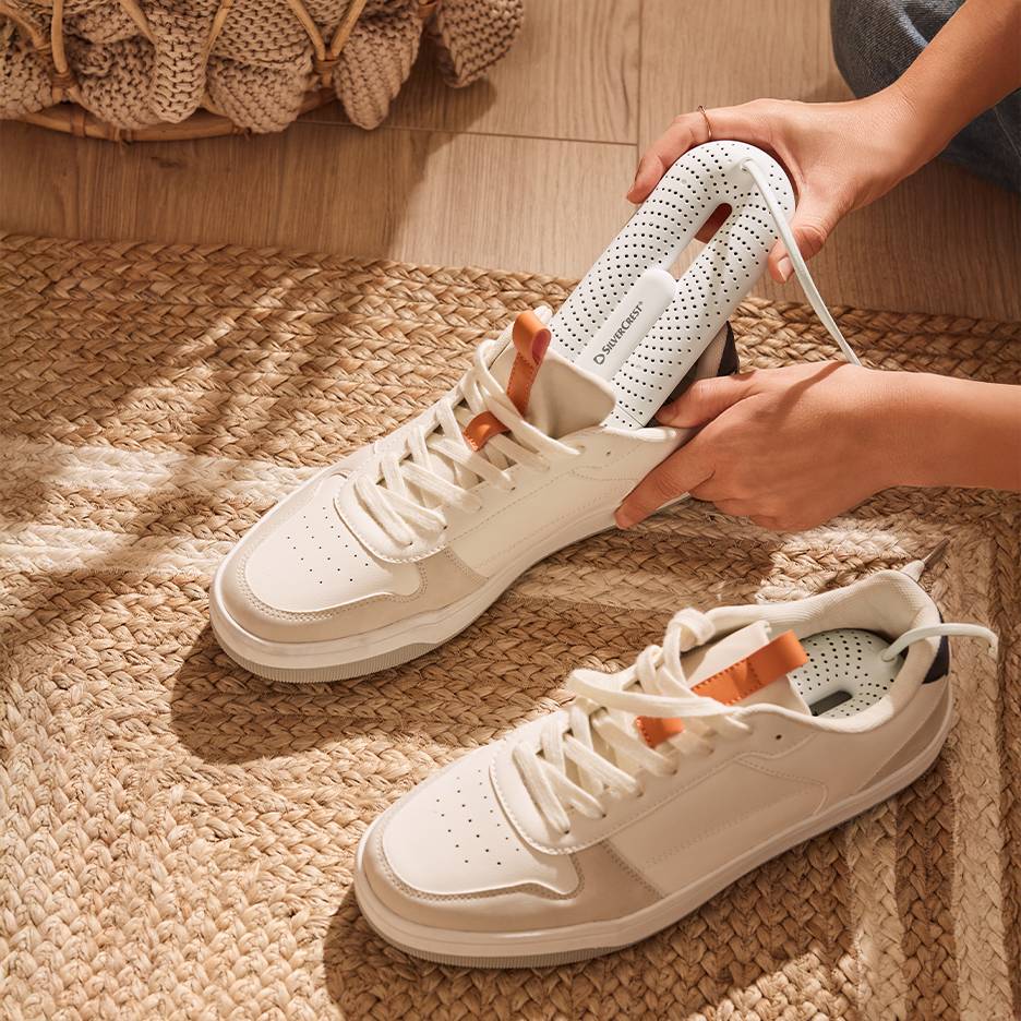 Silvercrest Schuhtrockner in weißen Sneakern auf einem geflochtenen Teppich.