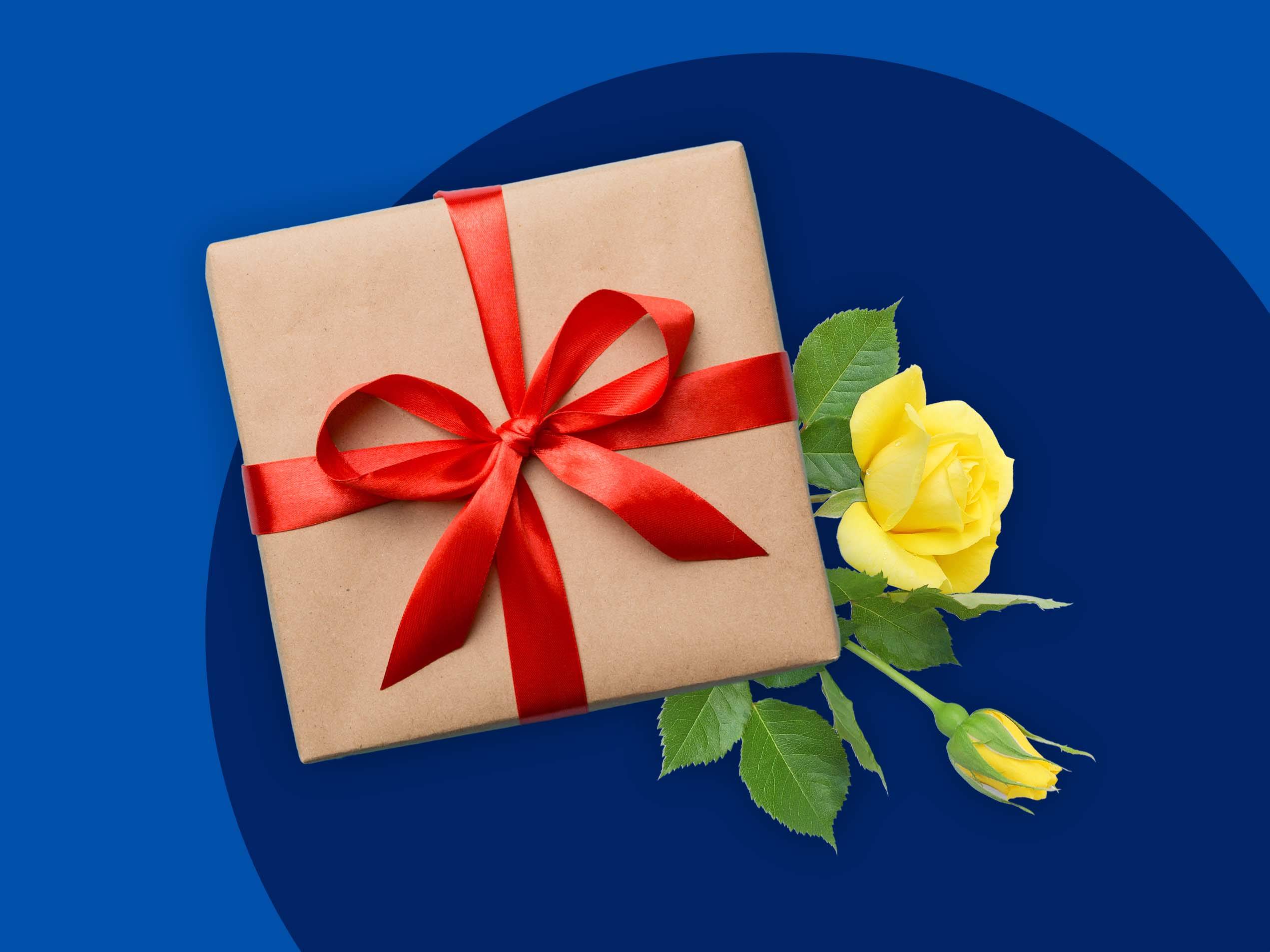 Ein Geschenkpaket mit roter Schleife und gelber Rose auf blauem Hintergrund.