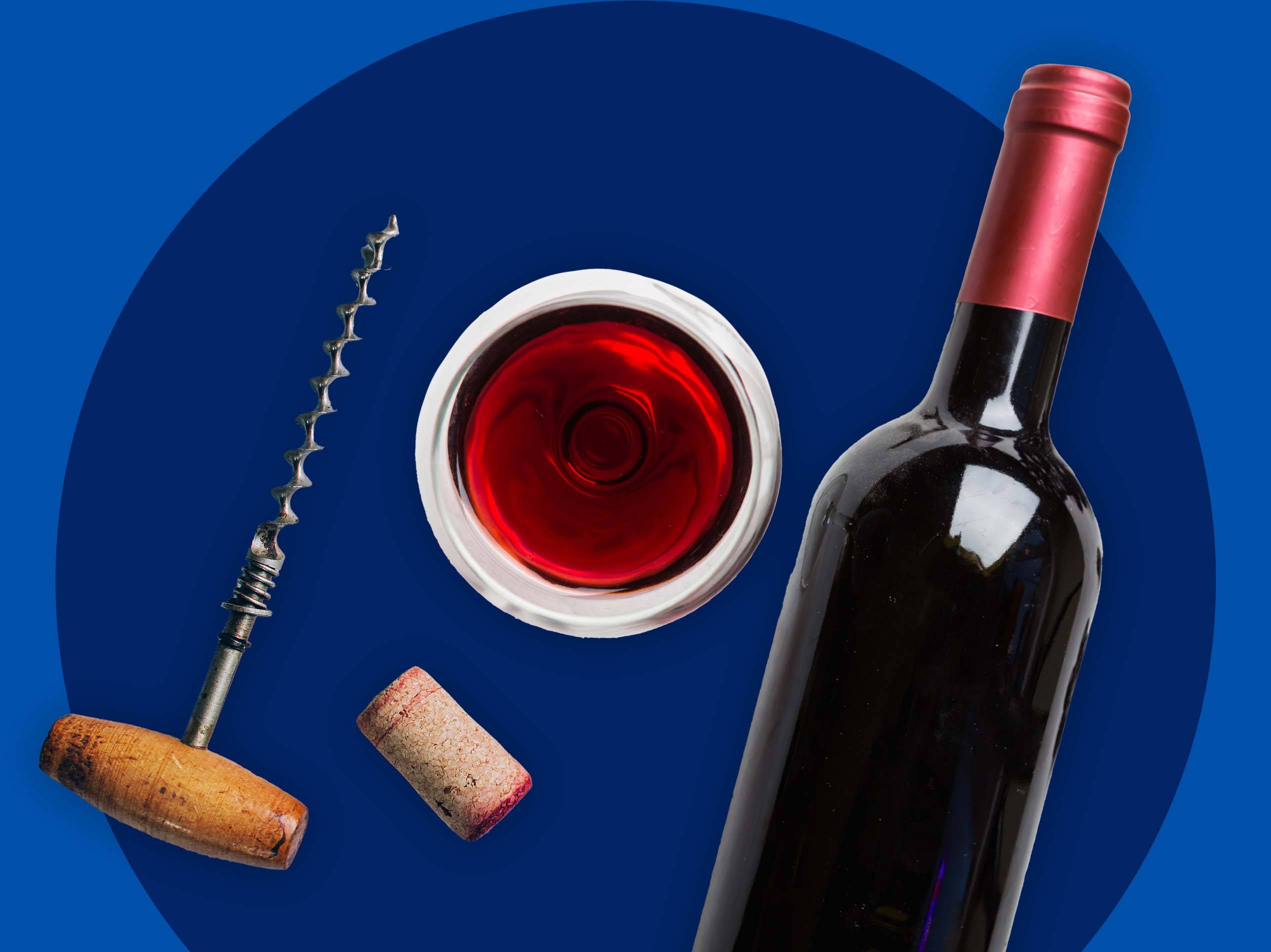 Eine Flasche Rotwein, ein Weinglas, ein Korkenzieher und ein Korken auf blauem Hintergrund.