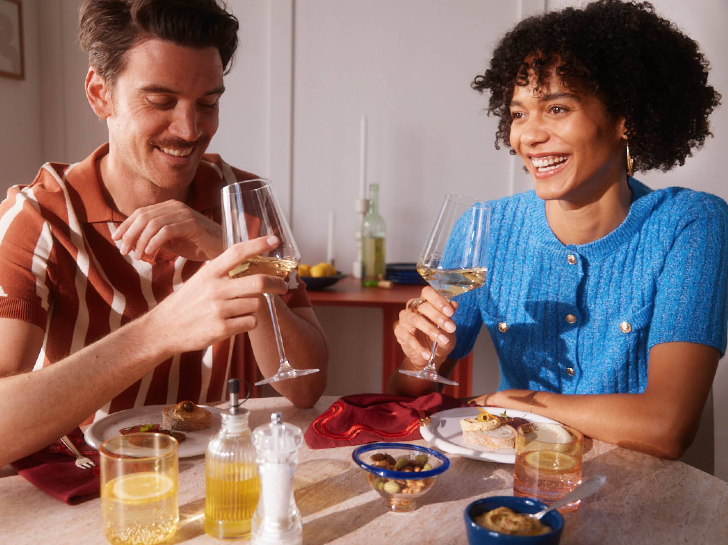 Ein Paar genießt ein Glas Wein und kleine Häppchen bei Tisch.