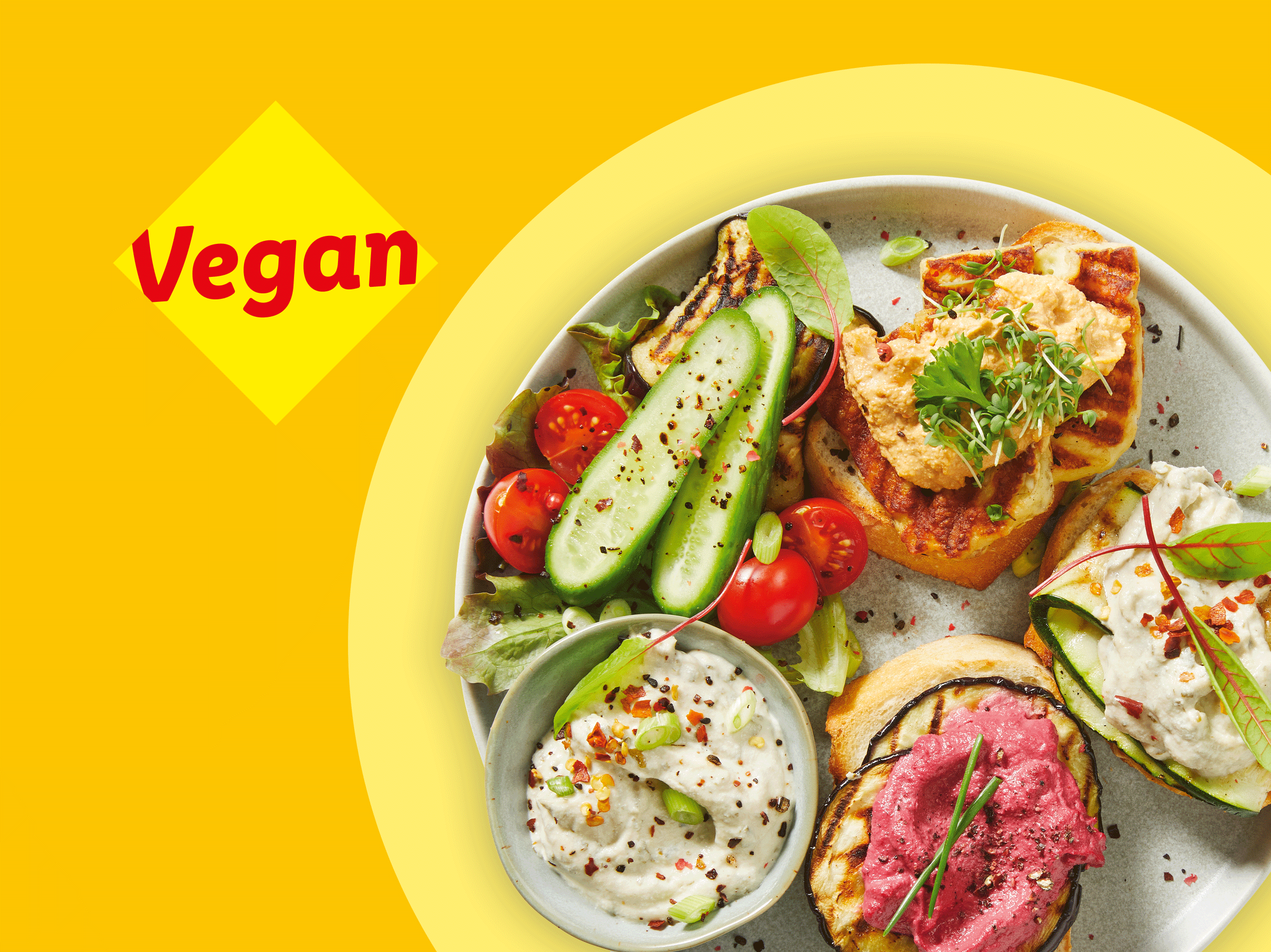 Vegane Bruschetta mit verschiedenen Aufstrichen, Gemüse und Salat auf einem Teller.