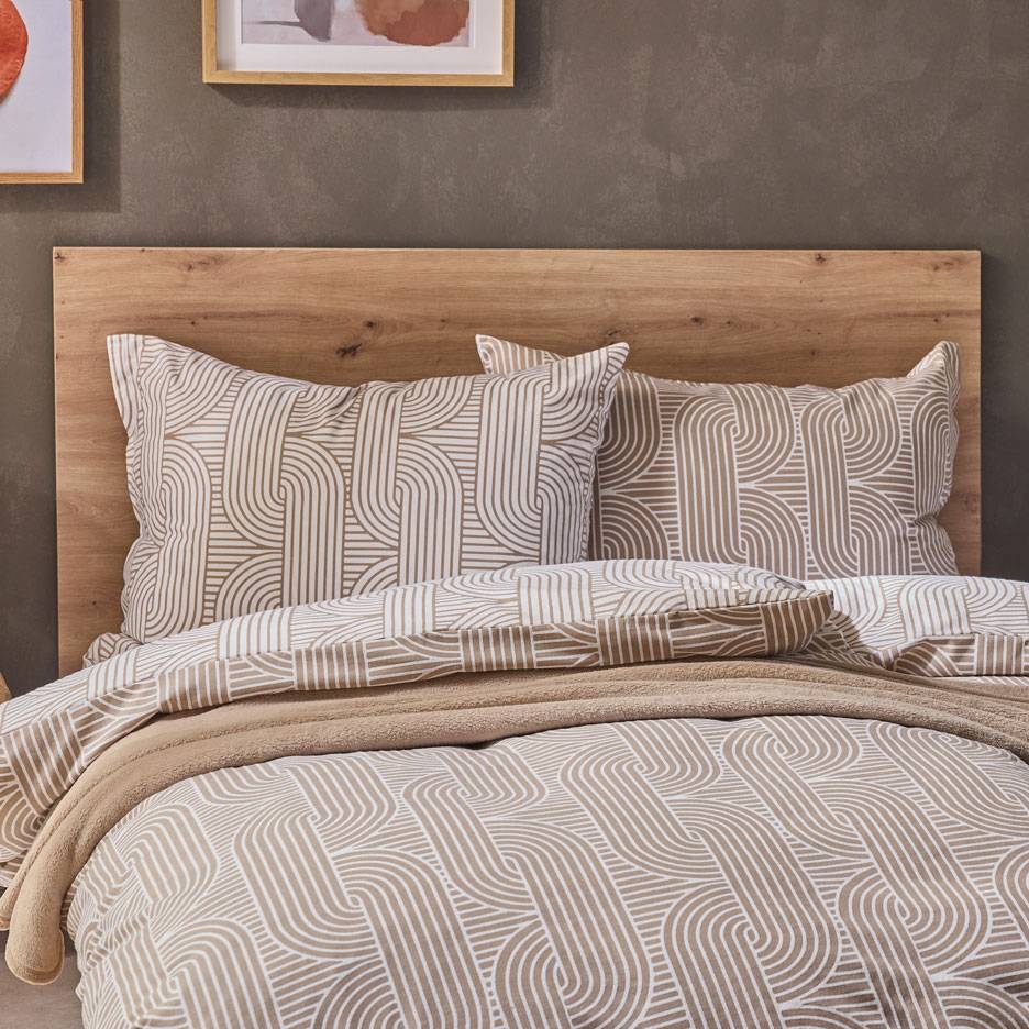 Bettwäsche mit braun-weißem geometrischem Muster, eine weiche Decke auf einem Holzbett.