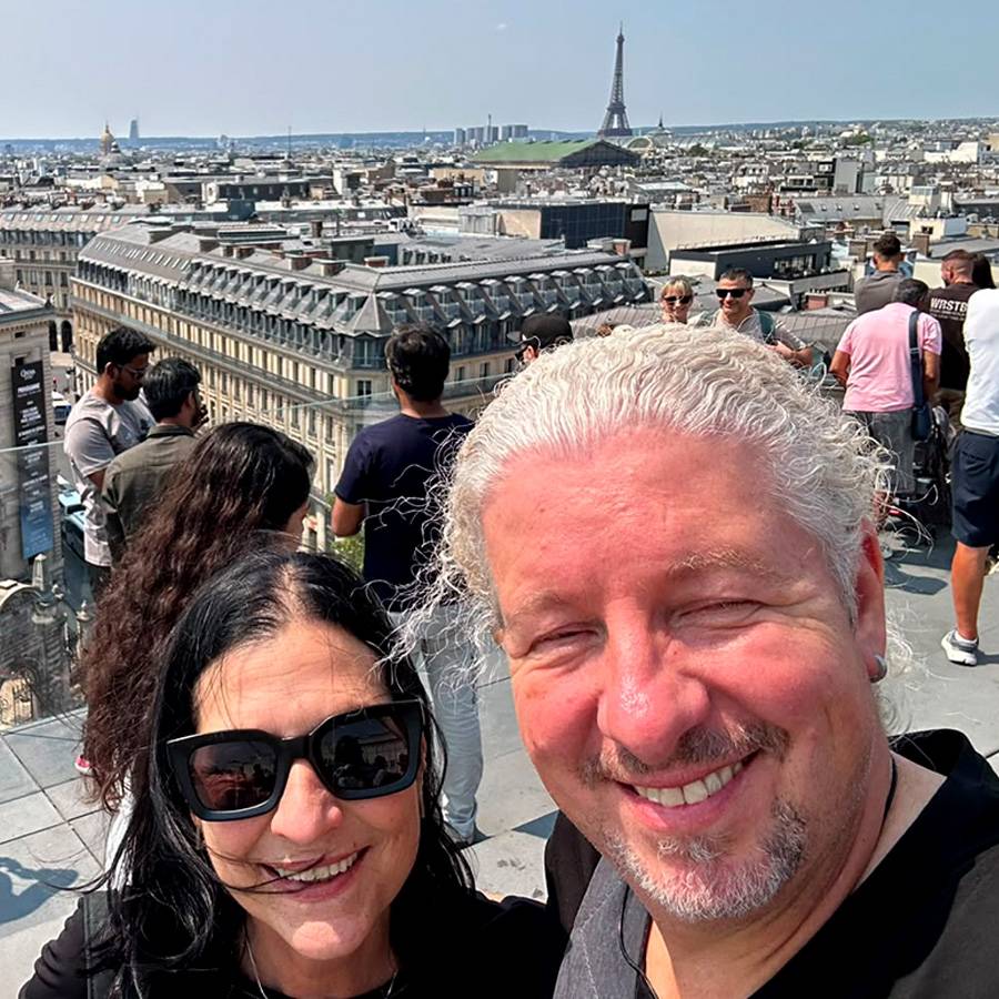 Paar macht Selfie mit Pariser Skyline und Eiffelturm im Hintergrund.