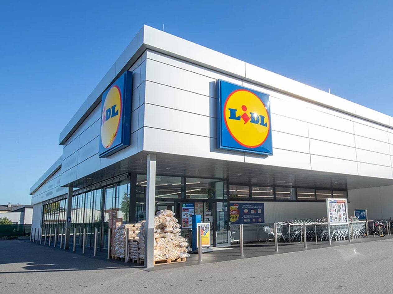 Ein Lidl-Supermarktgebäude mit dem Logo an der Fassade und Einkaufswagen davor.