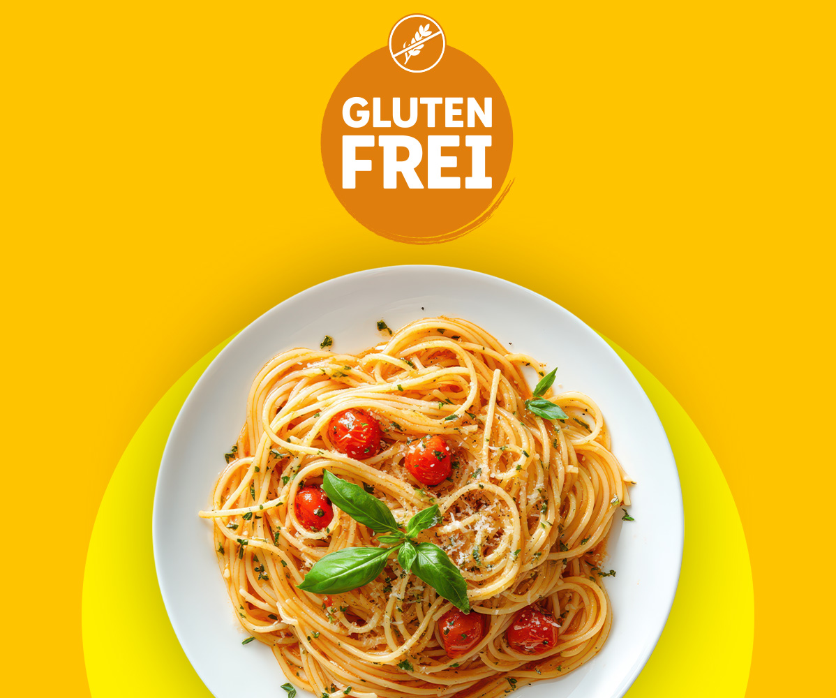 Glutenfreie Spaghetti mit Tomaten und Basilikum auf gelbem Hintergrund.