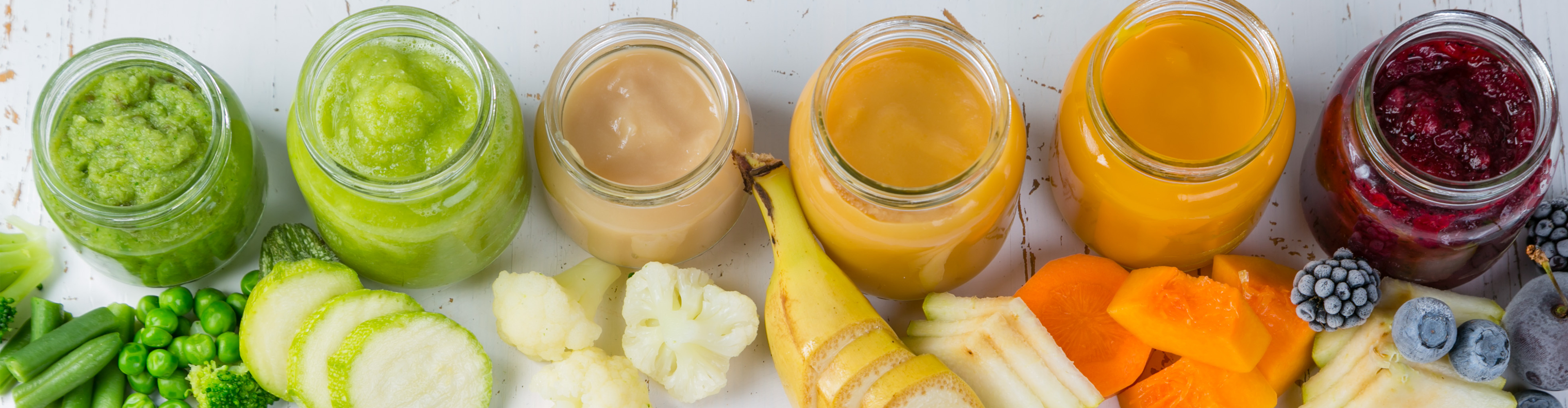 Gläser mit Babybrei in verschiedenen Farben und frische Zutaten