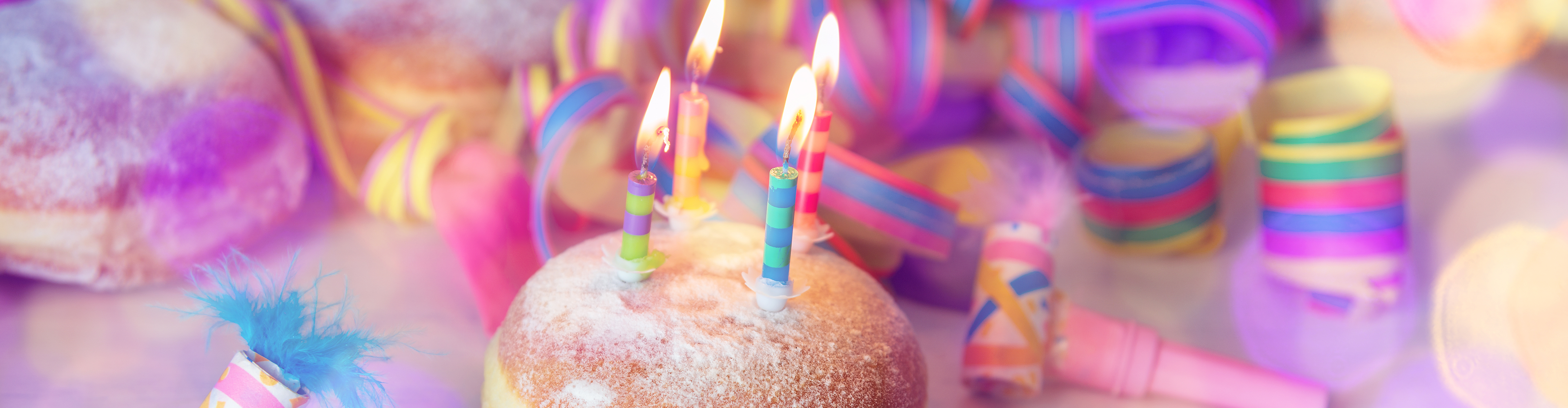 Berliner mit brennenden Kerzen, umgeben von bunten Partydekorationen