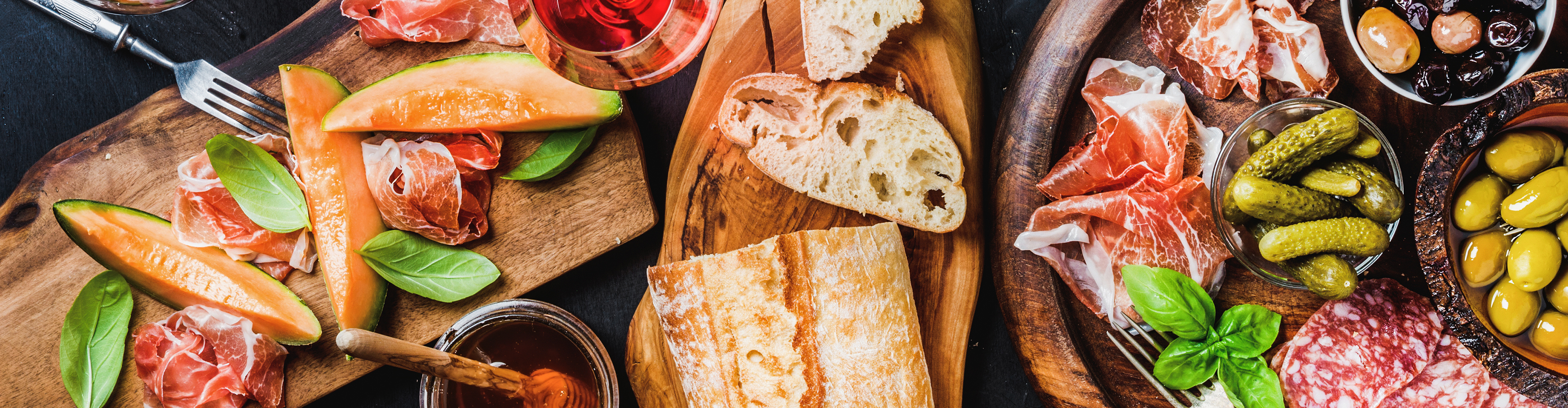 Aufschnittplatte mit Melone, Schinken, Brot, Oliven und Essiggurken