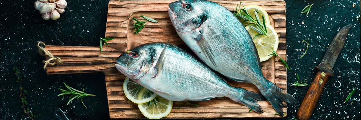 2 Fische am Brett werden fürs Grillen zubereitet