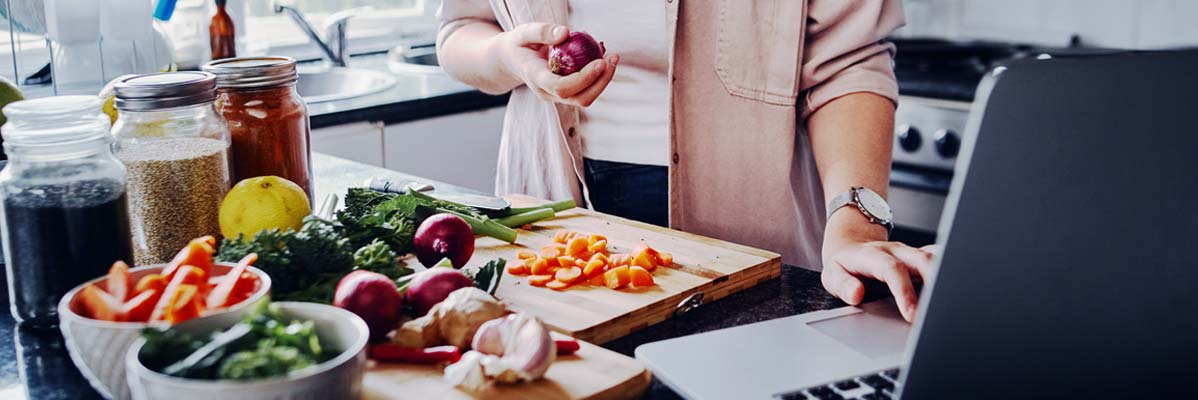 Ernährungsexpertin steht vor frischem geschnittenen Obst und Gemüse in der Küche
