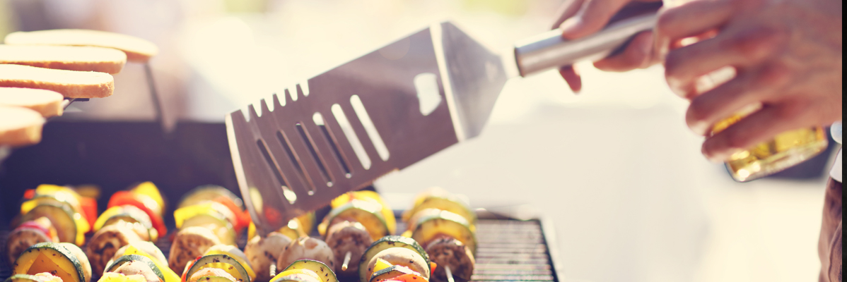 Spieße am Grill und Menschen im Hintergrund