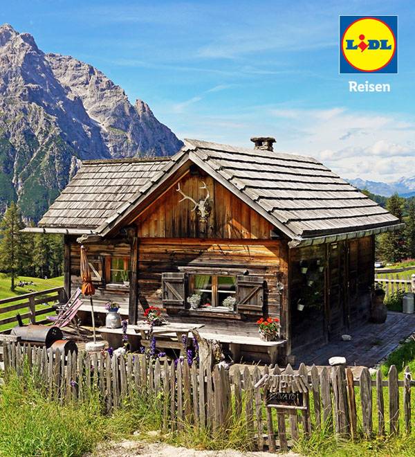 LIDL Reisen Werbung: Idyllisches Holzhaus in den Alpen.