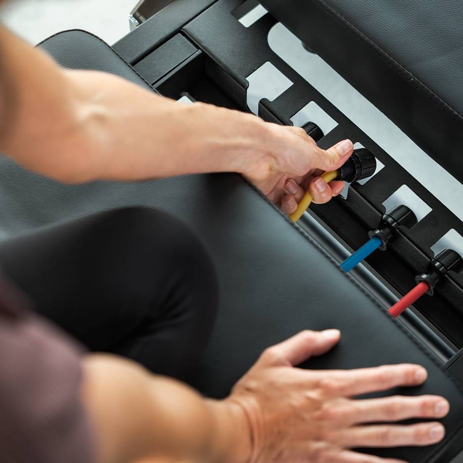 Person passt Widerstandsbänder an einer Trainingsbank an.