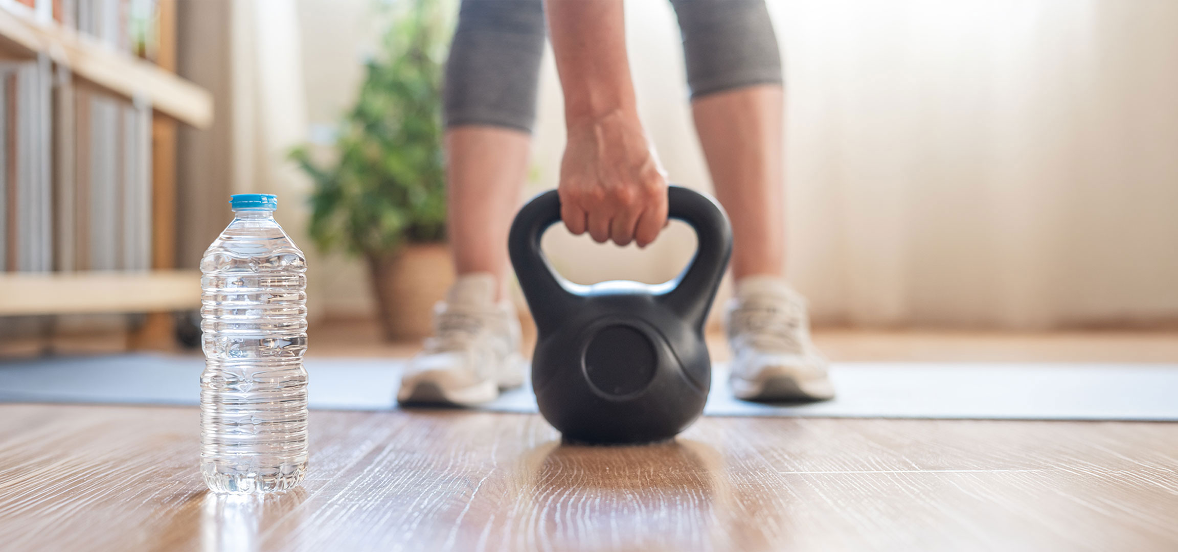 KI-generiert: Frau bereitet sich auf das Training mit einer Kettlebell und einer Wasserflasche auf einer Yogamatte vor.