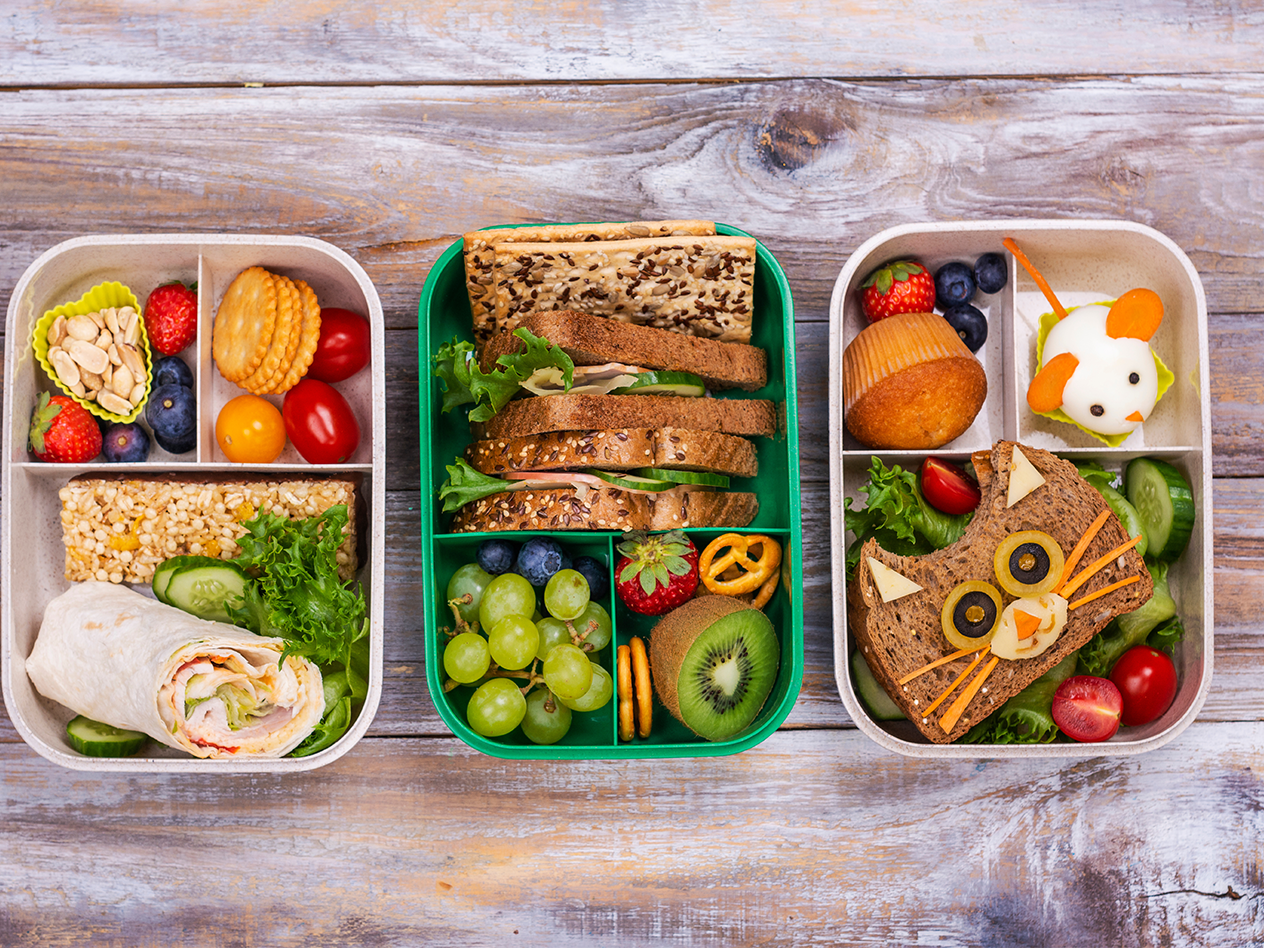 Drei Bento-Boxen mit Sandwiches, Wraps, Obst, Gemüse und Snacks für Kinder