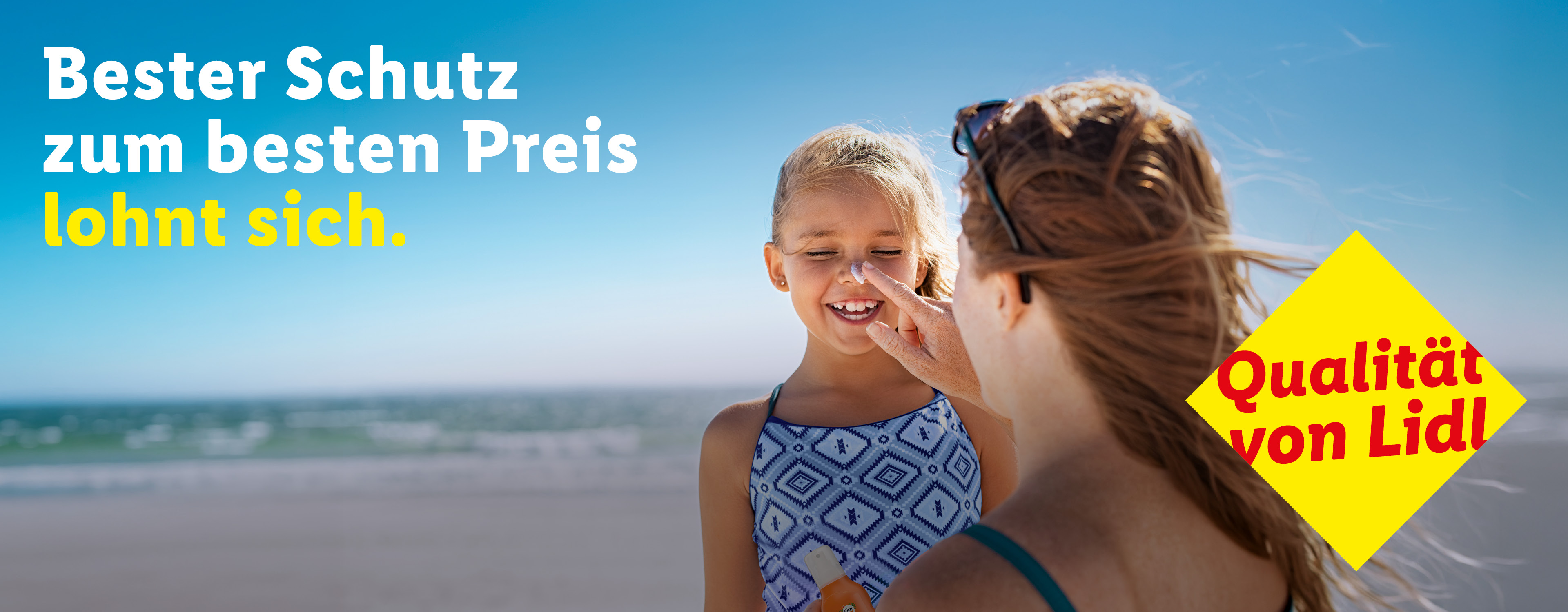 Mutter cremt Kind am Strand mit Sonnencreme ein. Text: Bester Schutz zum besten Preis lohnt sich. Qualität.