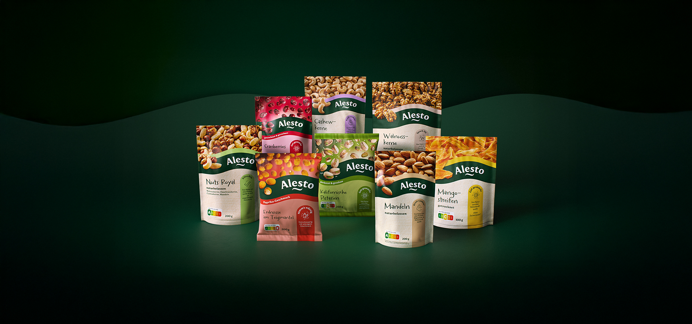 Verschiedene Snackbeutel mit Nüssen, Trockenfrüchten und gewürzten Erdnüssen auf dunkelgrünem Hintergrund.
