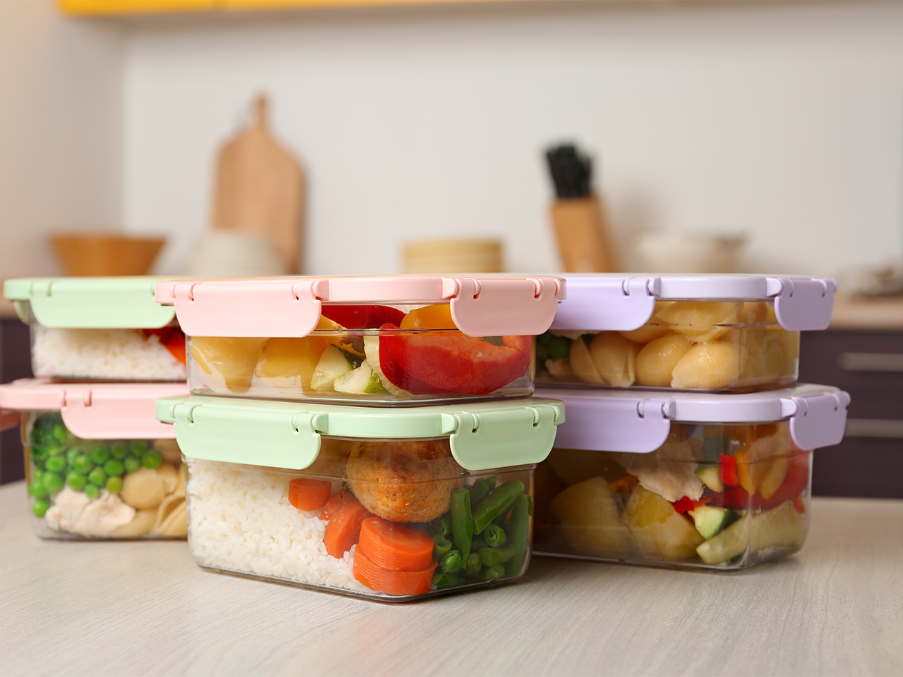 Mehrere Frischhaltedosen mit verschiedenen Mahlzeiten auf einer Küchentheke.