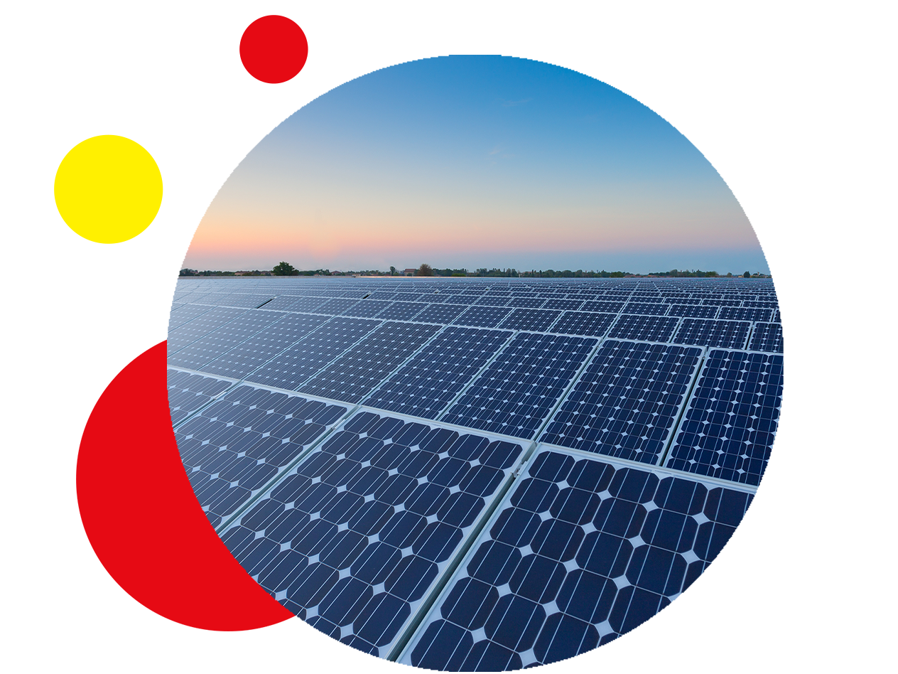 Ein großes Feld mit Solarmodulen unter einem farbenfrohen Himmel bei Sonnenuntergang.