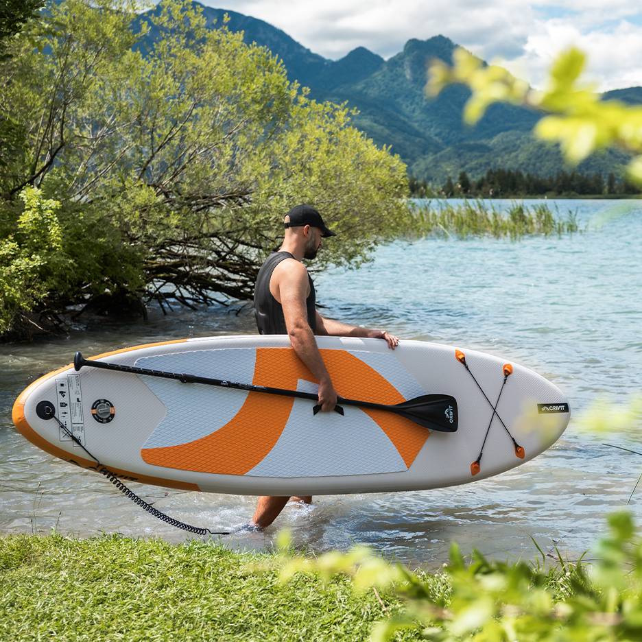Mann mit CRIVIT Stand-Up-Paddle-Board im Wasser, bereit zum Paddeln.