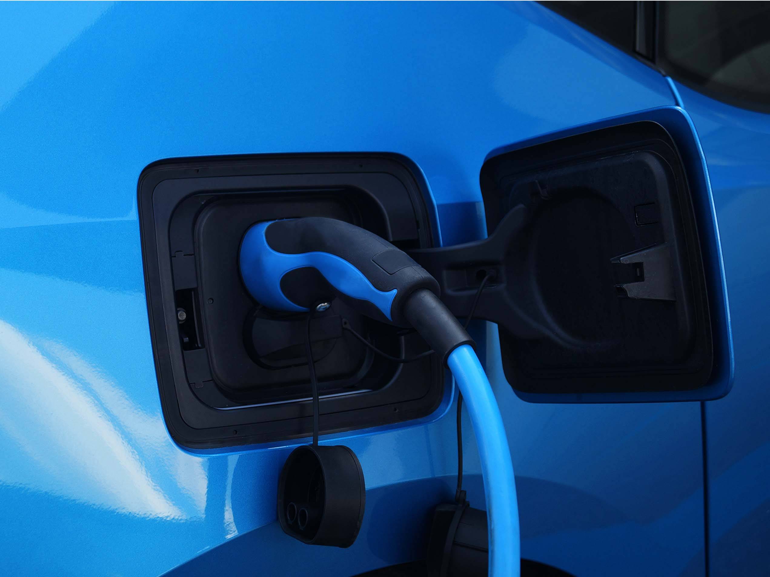 Ein blaues Elektroauto wird mit einem blauen Ladekabel aufgeladen.
