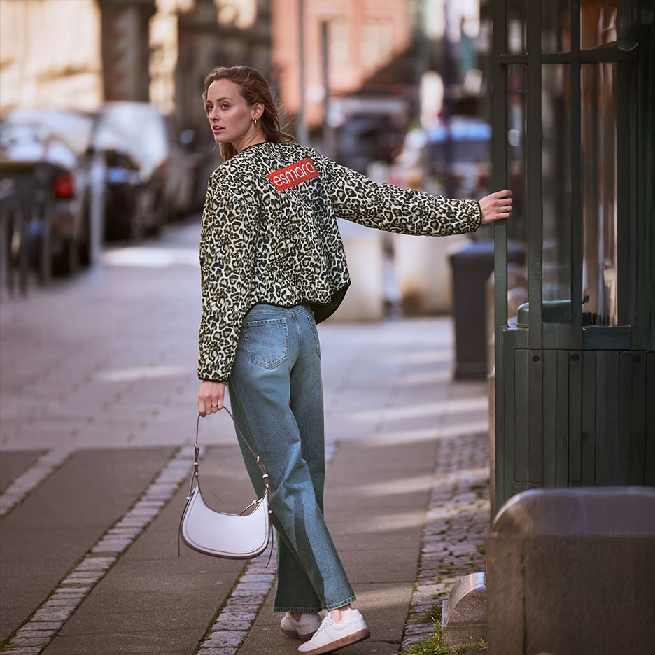 Frau in Esmara Leo-Jacke und Jeans, mit Handtasche, auf der Straße.