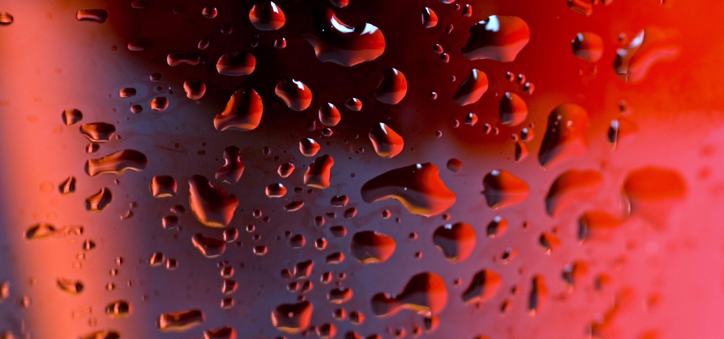 Rote Wassertropfen auf einer Oberfläche mit verschwommenem Hintergrund