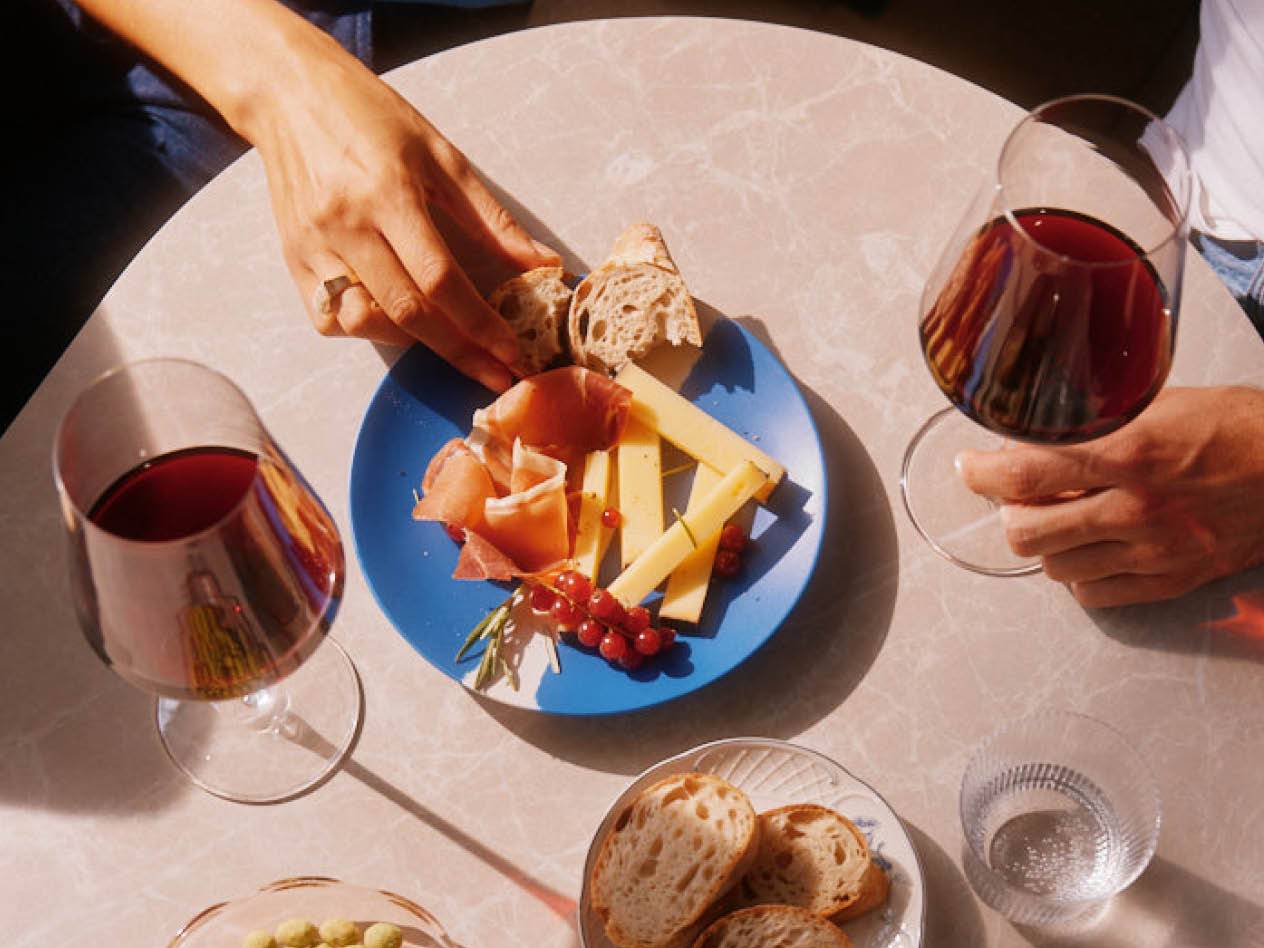 Ein Tisch mit Käse, Brot und zwei Gläsern Wein.